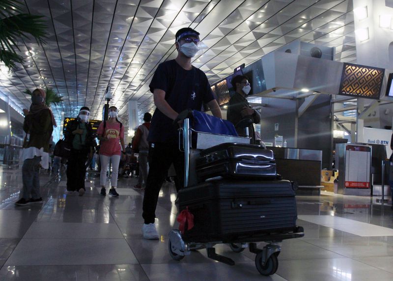 Passengers wearing protective face masks walk at the Soekarno-Hatta Airport,