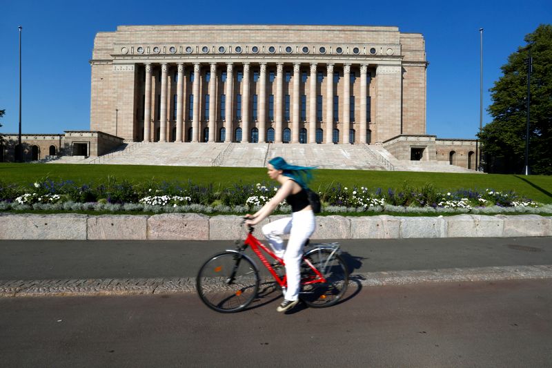 FILE PHOTO: A woman rides a bike past Finland’s Parliament
