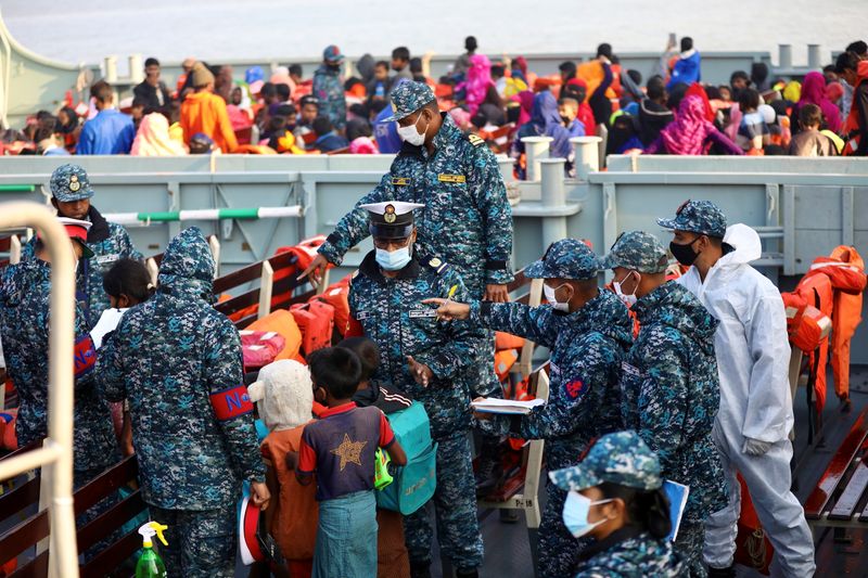 Bangladesh navy personnel check Rohingyas before they board a ship
