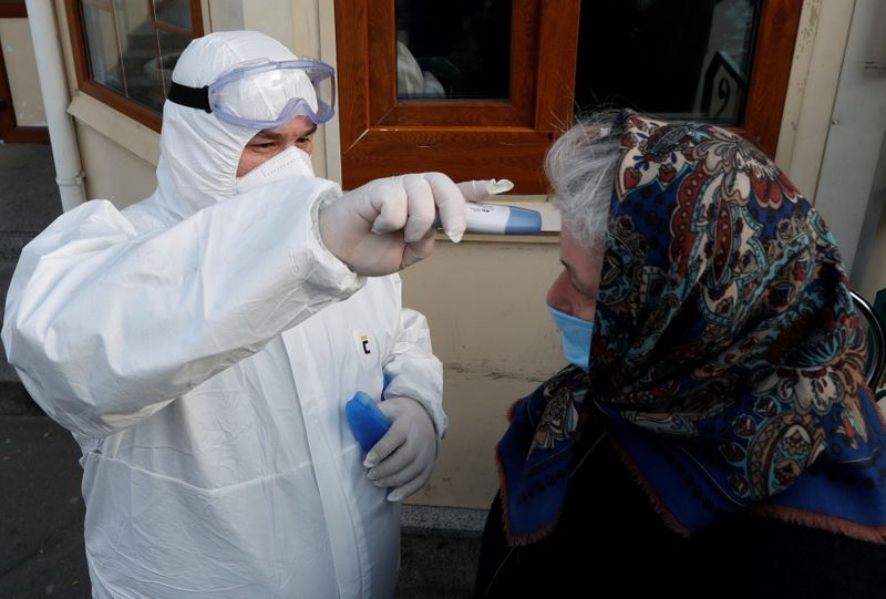 A health worker measures the temperature of a woman at