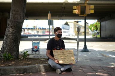 A Venezuelan immigrant makes a plea for money on a