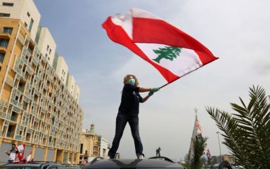 An anti-government demonstrator holds a Lebanese flag as she stands