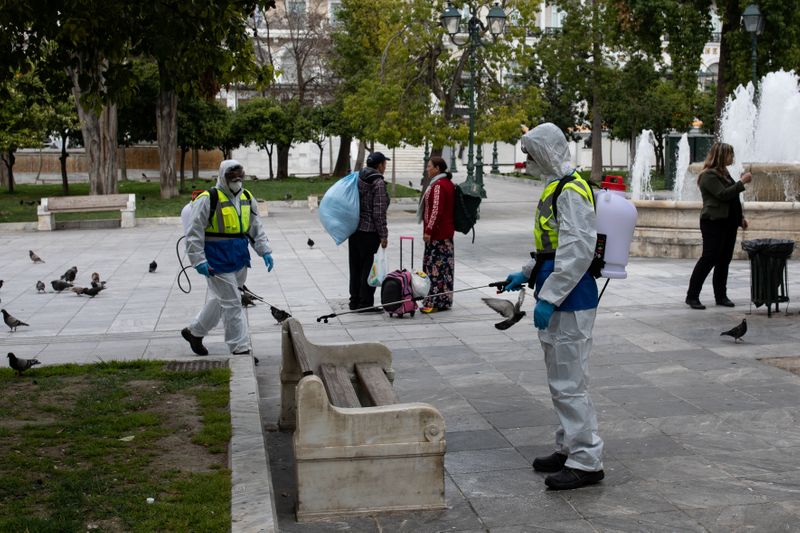 Municipal workers wearing protective suits disinfect Syntagma square, after the