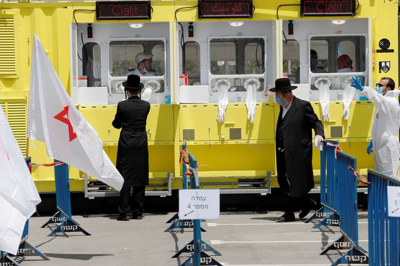 Ultra orthodox Jewish men stand by a testing station for
