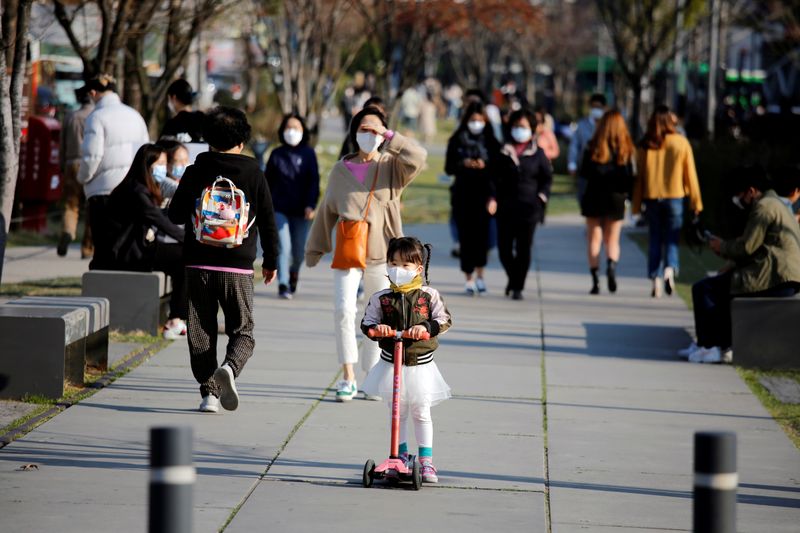FILE PHOTO: A girl wearing a protective face mask rides