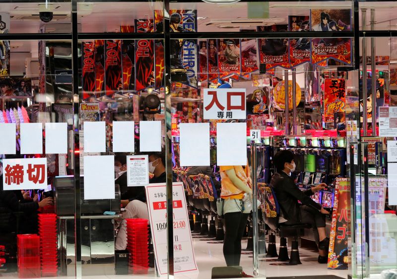 Visitors play pachinko, a Japanese form of legal gambling, at