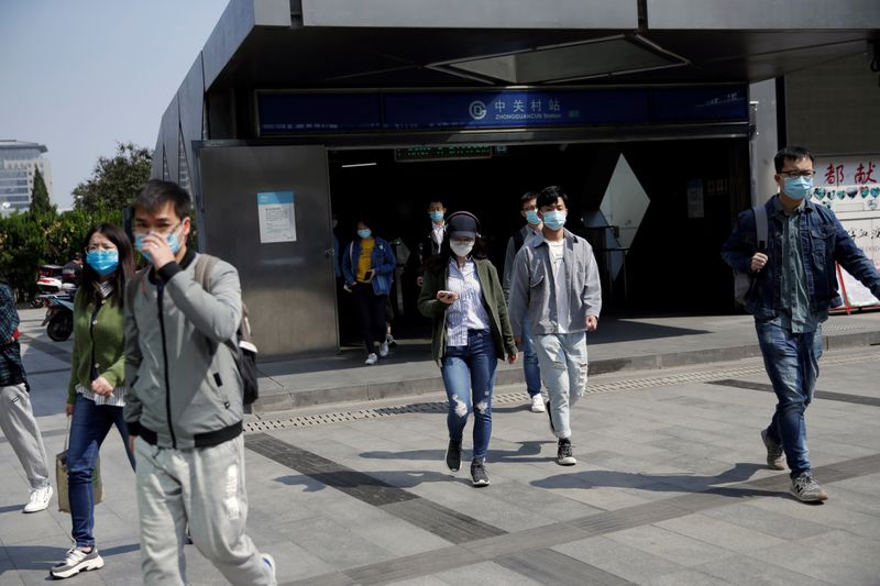 People wearing face masks walk out of Zhongguancun subway station