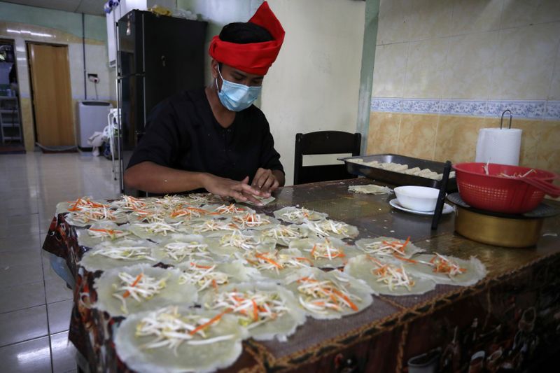 An online Ramadan bazaar trader wraps “Popiah” spring rolls at