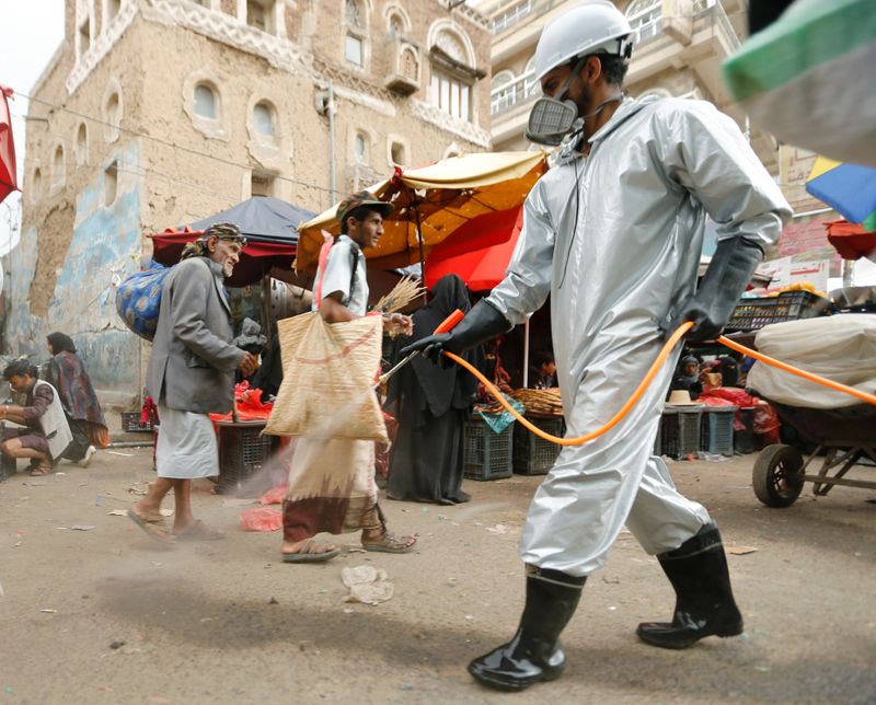 A health worker wearing a protective suit disinfects a market