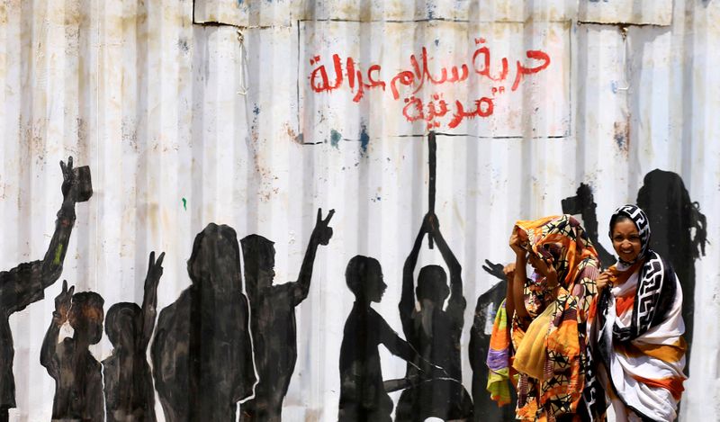 FILE PHOTO: Civilians walk past graffiti reading in Arabic “Freedom,