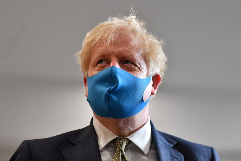 Britain’s Prime Minister Boris Johnson, wearing a face mask, visits