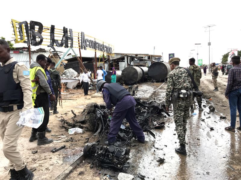 Somali security officers assess the wreckage of a car destroyed