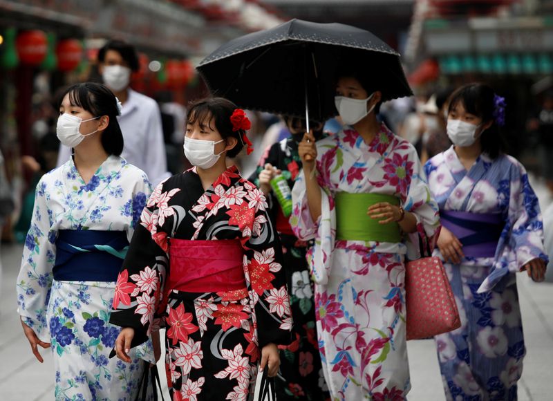 Women in yukata, or casual summer kimonos, wearing protective face