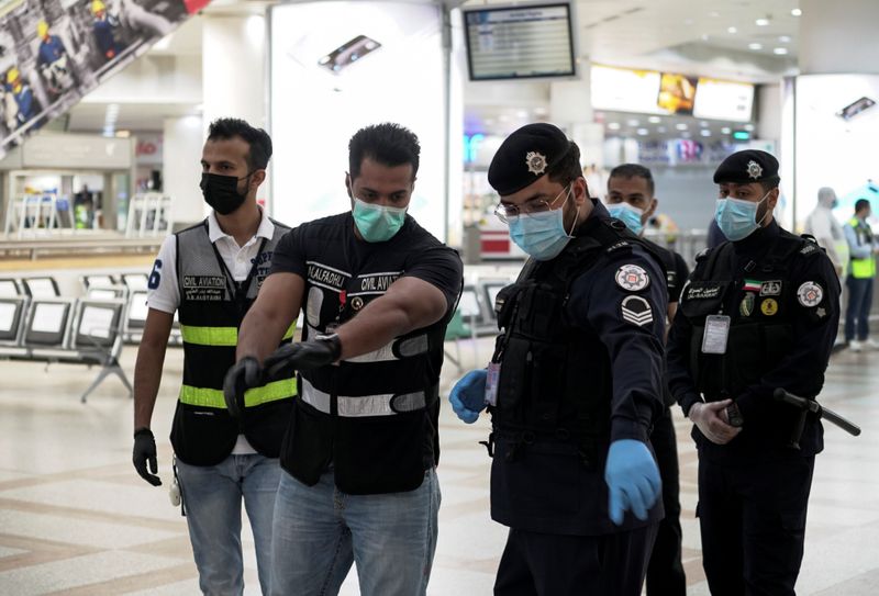 Police and civil aviation personnel wearing protective face masks work