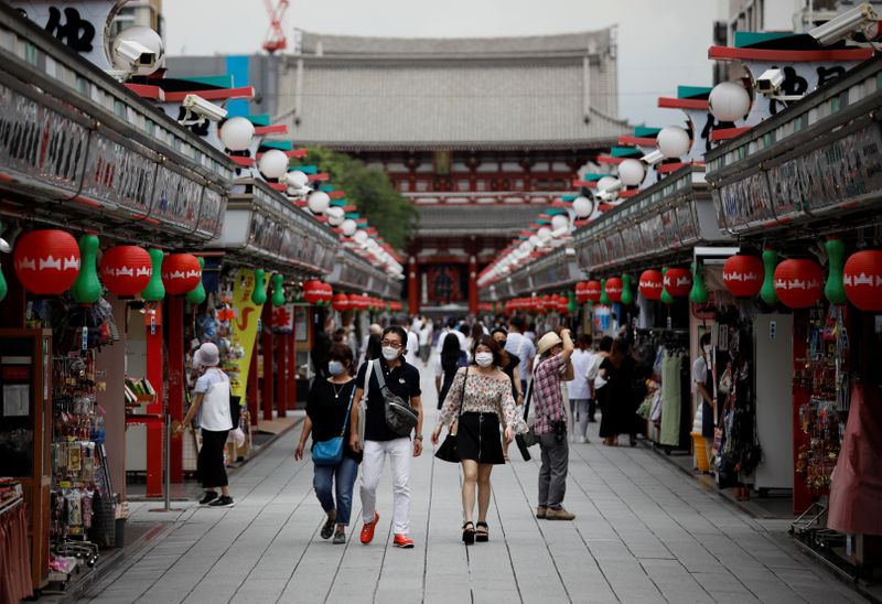 Visitors wearing protective face masks walk at Asakusa district amid