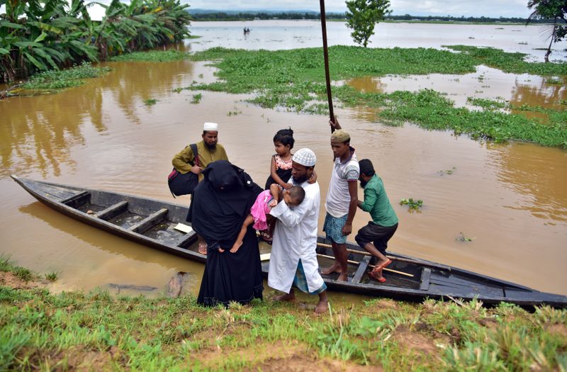 Flood-affected villagers disembark a boat after they reached a safer