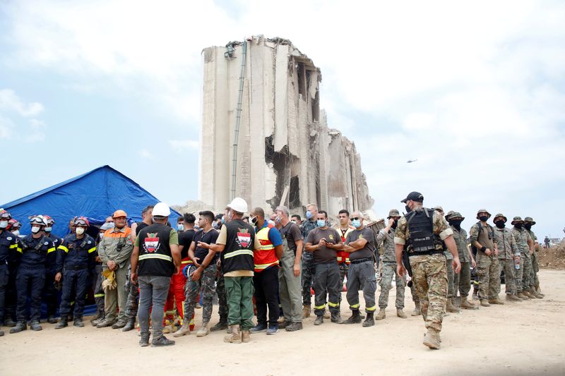 Soldiers and rescue workers stand at the devastated site of