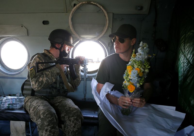 A Ukrainian presidential office official holds flowers inside a helicopter