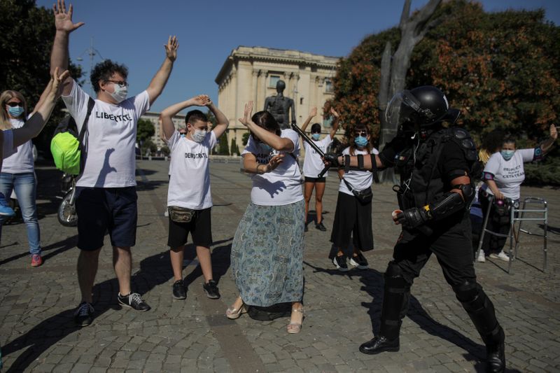 Activist Marian Raduna, dressed as a riot police officer, pretends