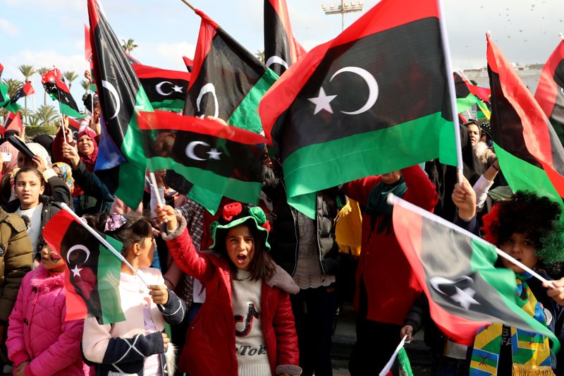 People wave Libyan flags as they gather during celebrations commemorating