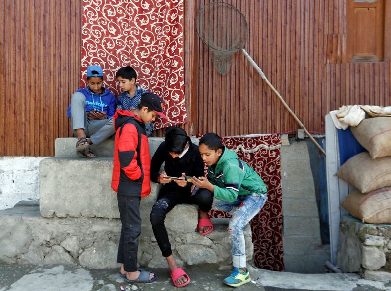 Children play games on their mobile phones in a neighbourhood