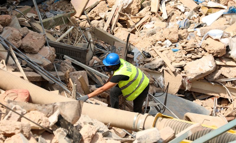 FILE PHOTO: A volunteer digs through the rubble of buildings