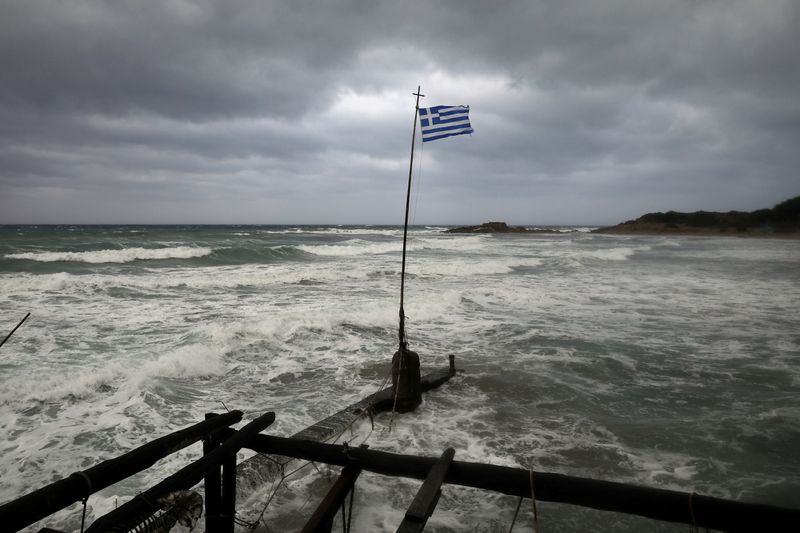 A Greek flag flatters in a beach near the town