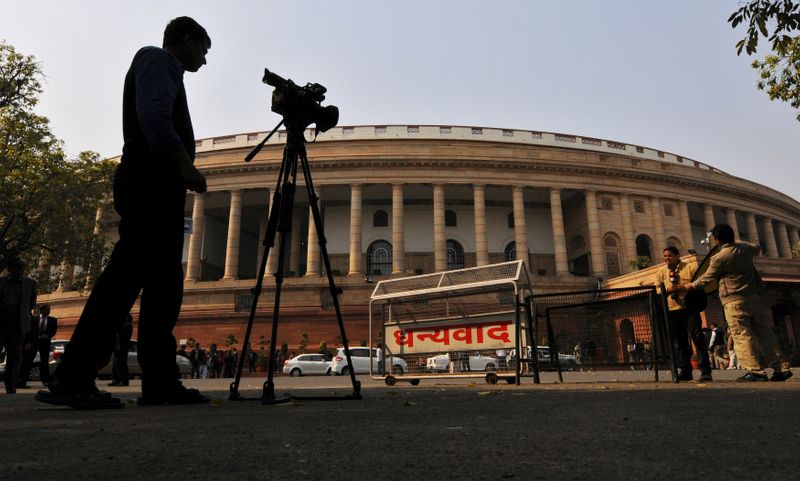Television journalists report from the premises of India’s Parliament in