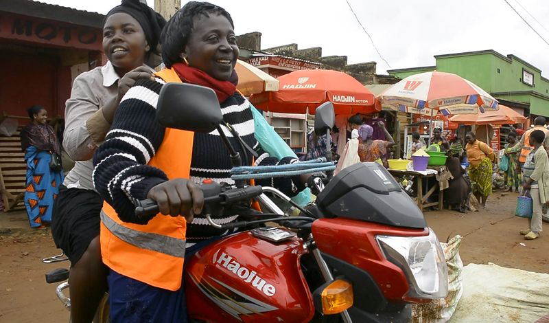 Congolese motorbike taxi rider Imelda Mmambu carries a client on