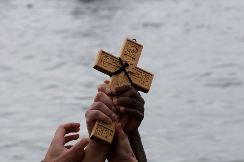 FILE PHOTO: Orthodox faithful raise a wooden crucifix during Epiphany