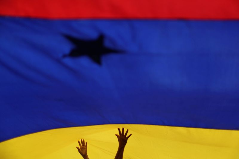 FILE PHOTO: Locals hold a flag in Caracas, Venezuela