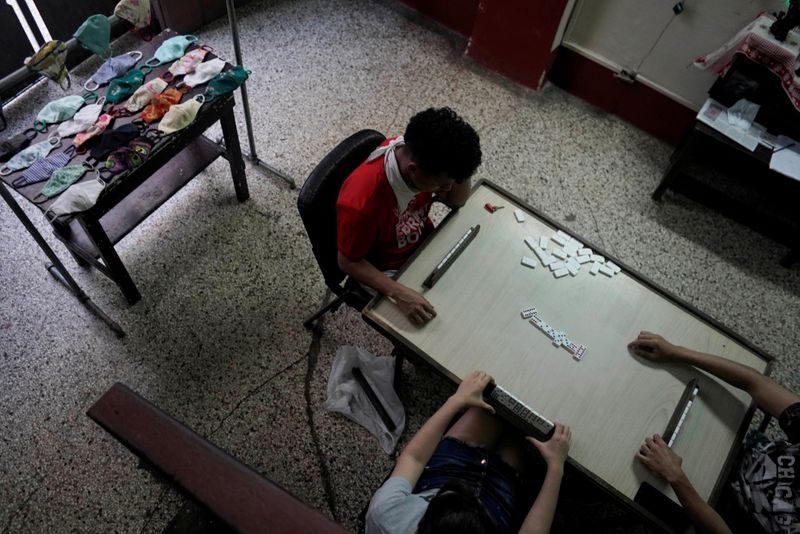 FILE PHOTO: Children play dominoes beside masks for sale in