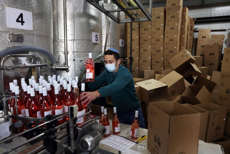 An employee sorts wine bottles as he works at Tura
