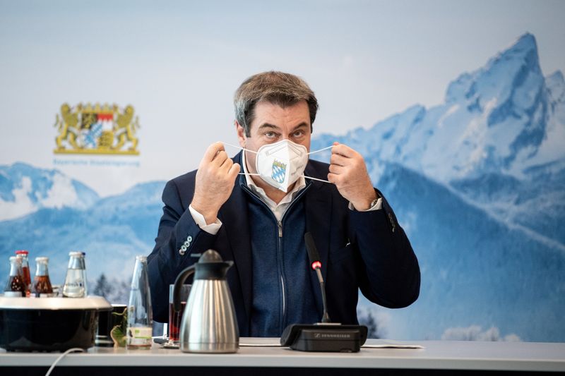 FILE PHOTO: Bavaria’s State Prime Minister Markus Soeder removes his
