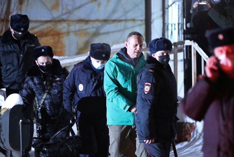 Russian opposition leader Alexei Navalny is escorted by police officers