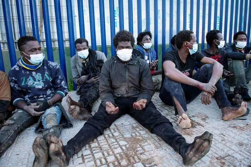 Migrants sit outside the temporary migrants center upon crossing the