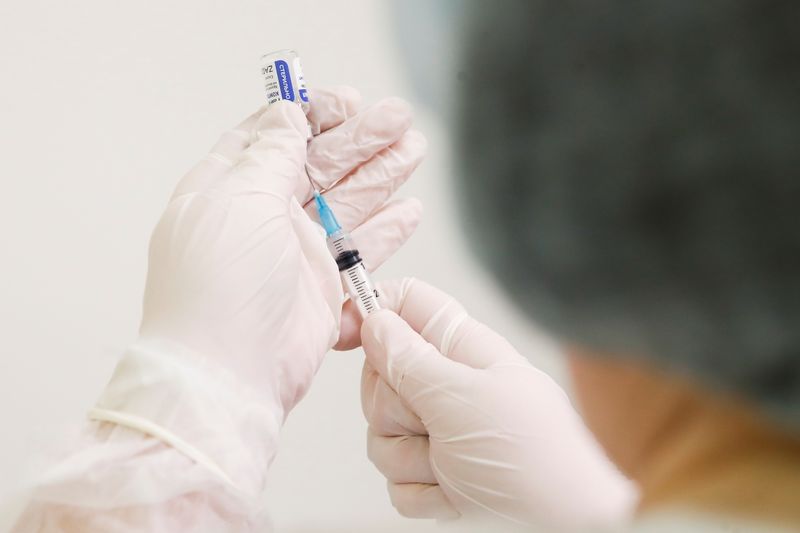 A healthcare worker fills a syringe with a dose of