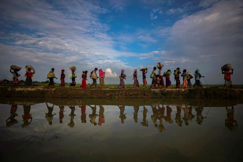 FILE PHOTO: Rohingya refugees are reflected in rain water along