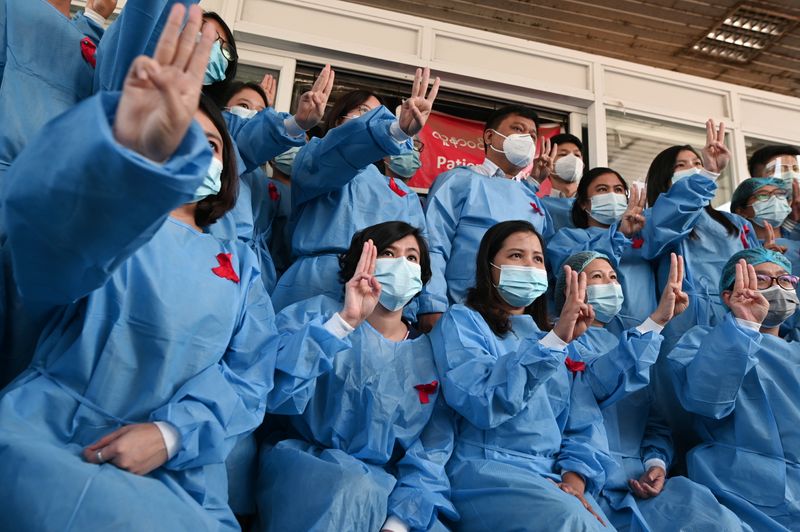 Medical workers wearing red ribbons pose during a protest against