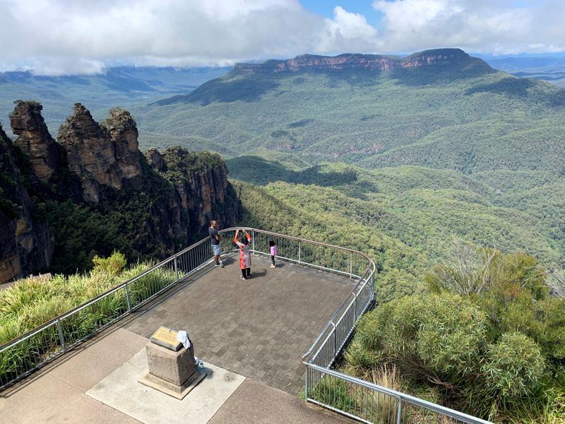 A family takes photos in front of The Three Sisters