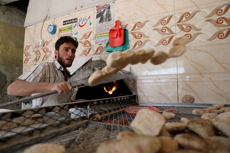 A baker takes out bread baked in a wood-fired oven