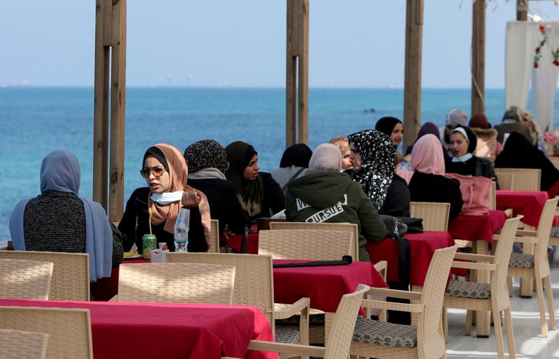 Palestinian women sit at a cafe on a beach in