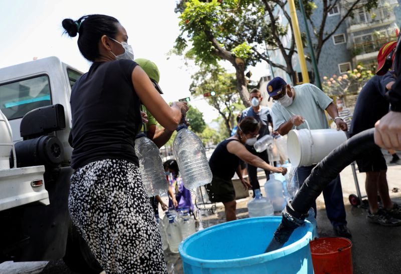FILE PHOTO: People collect water on a street in Caracas