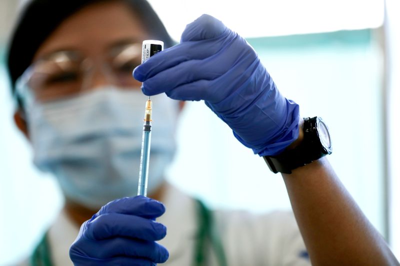 A medical worker fills a syringe with a dose of