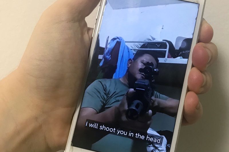 A mobile phone shows a picture of a Myanmar man