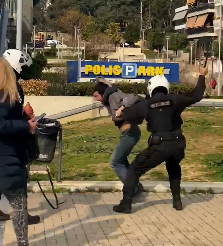 Police officers detain a man in Athens, in this screen