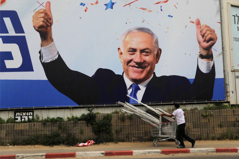 A man walks past a Likud party election campaign banner