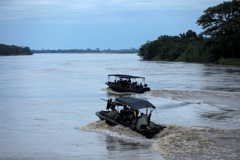 Colombian soldiers patrol by boat on the Arauca River, at