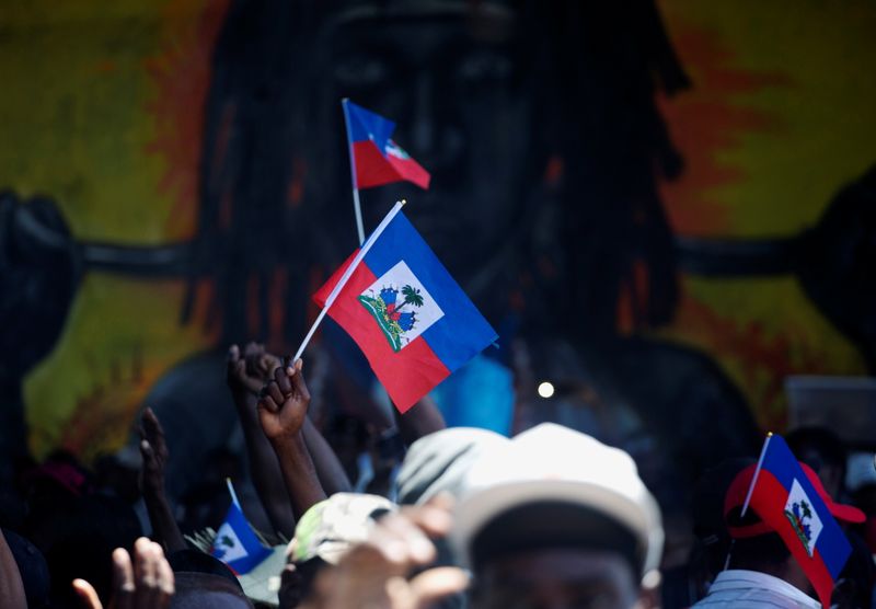 Demonstrators hold Haiti’s national flags during a protest against the
