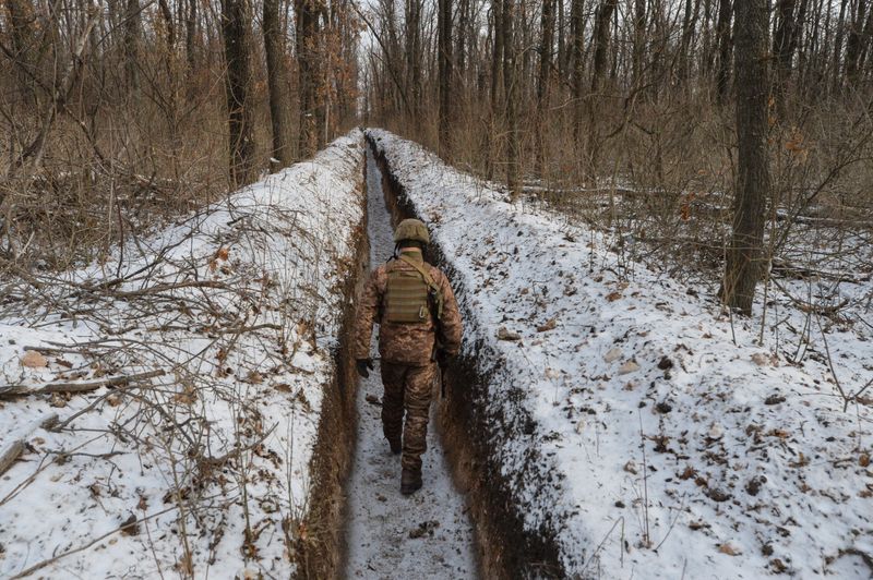 FILE PHOTO: A Ukrainian service member walks along fighting positions